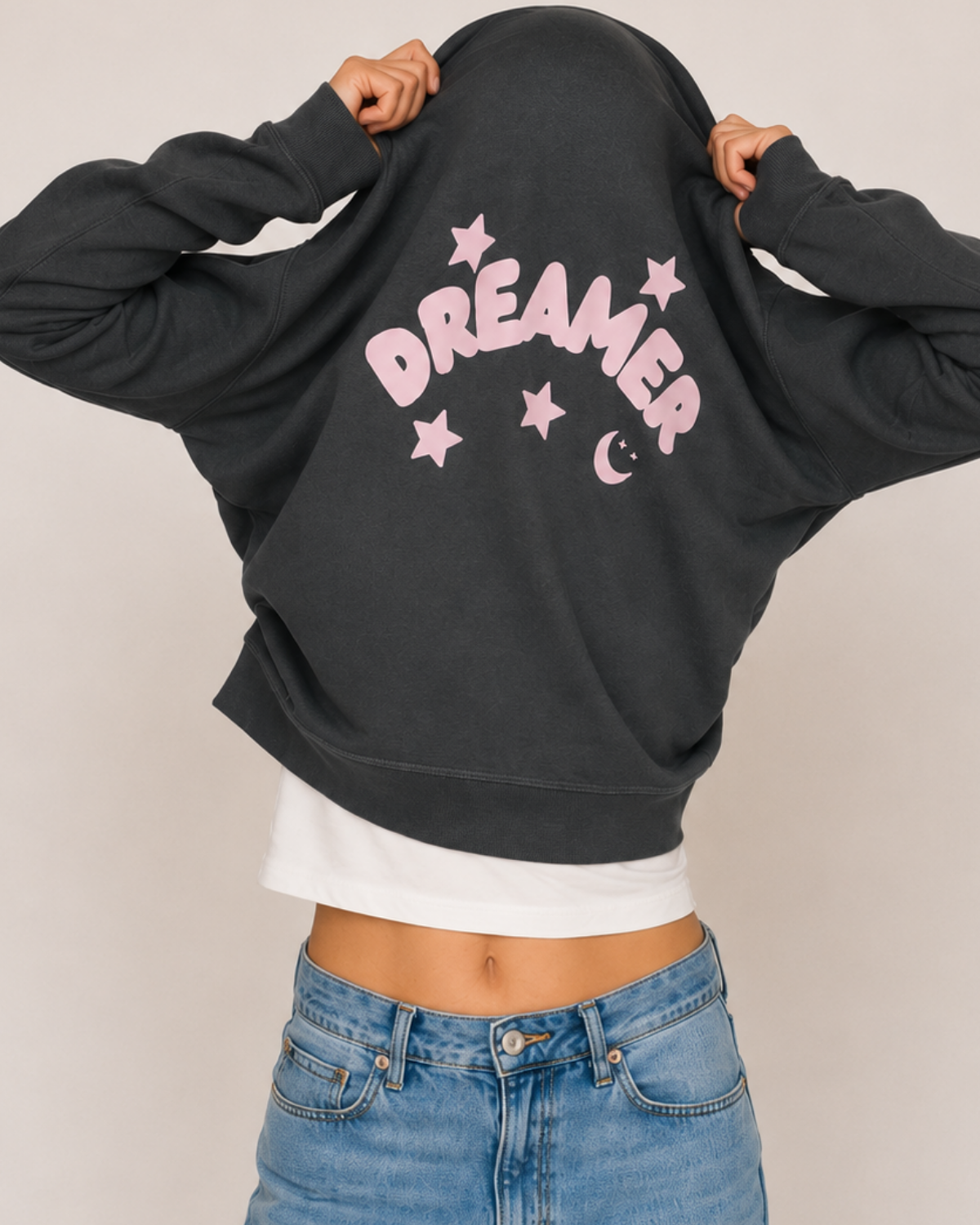 Person wearing a anthracite sweatshirt with 'Dreamer' printed on it, standing against a plain background.