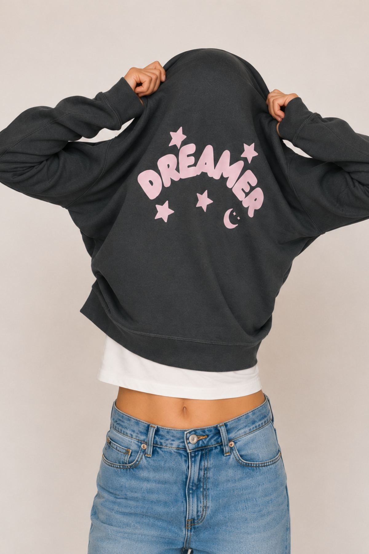 Person wearing a anthracite sweatshirt with 'Dreamer' printed on it, standing against a plain background.